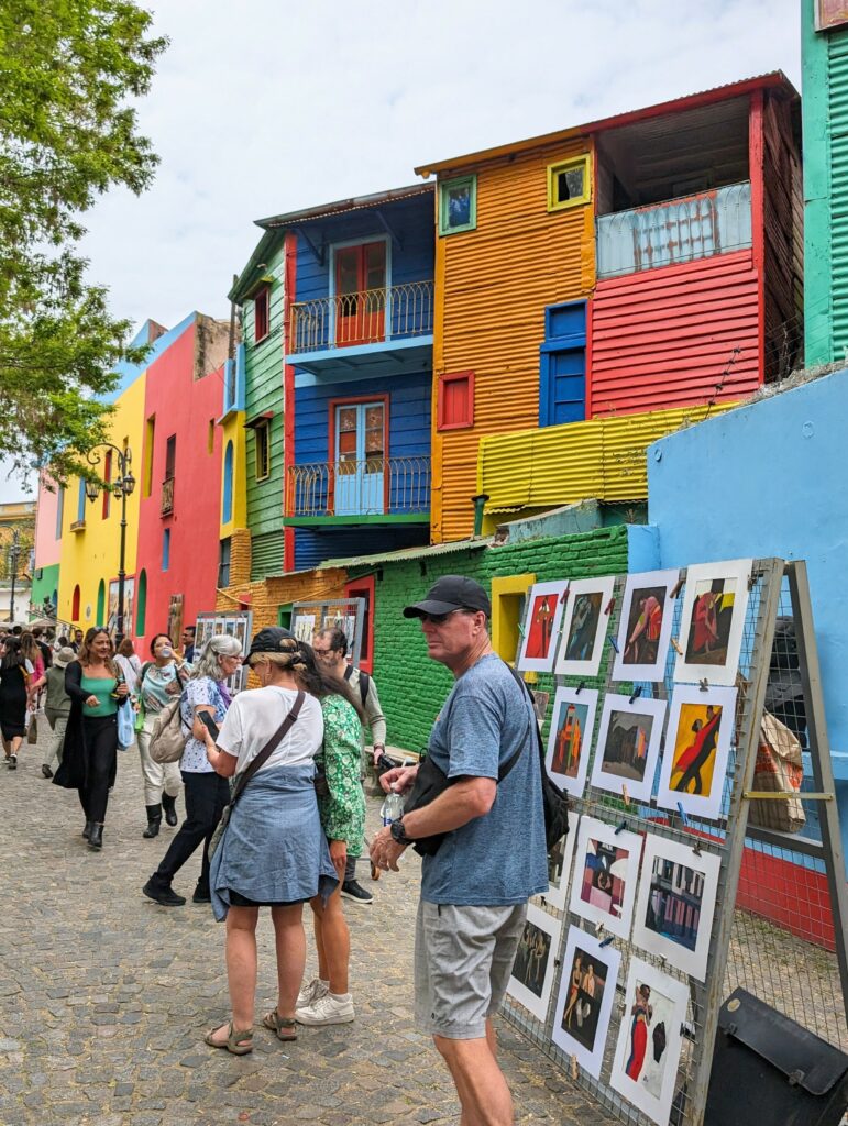 People walking through El Caminito in La Boca, Buenos Aires, Argentina with colorful buildings and artwork.