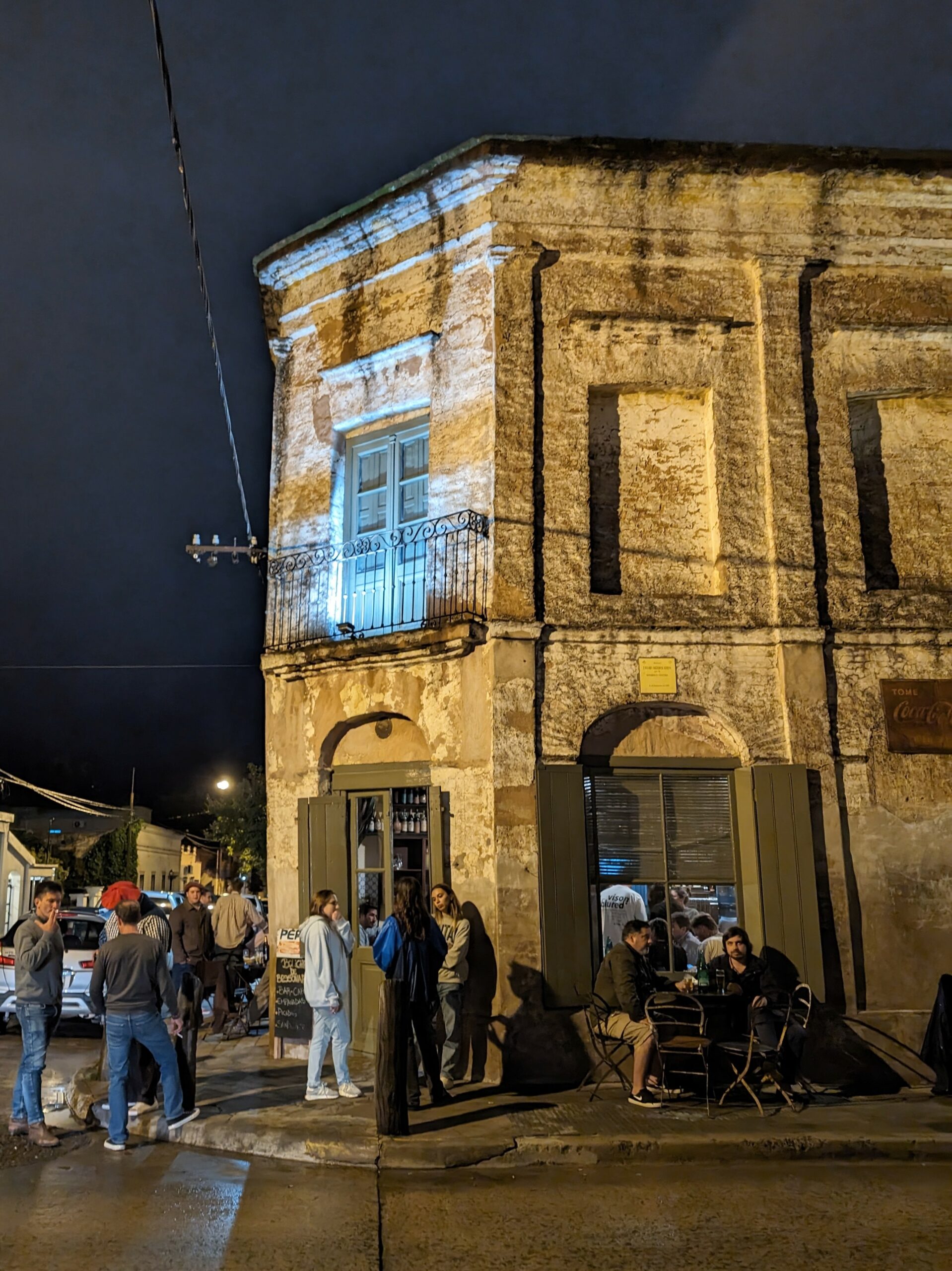 People hanging out outside of an old bar at night.