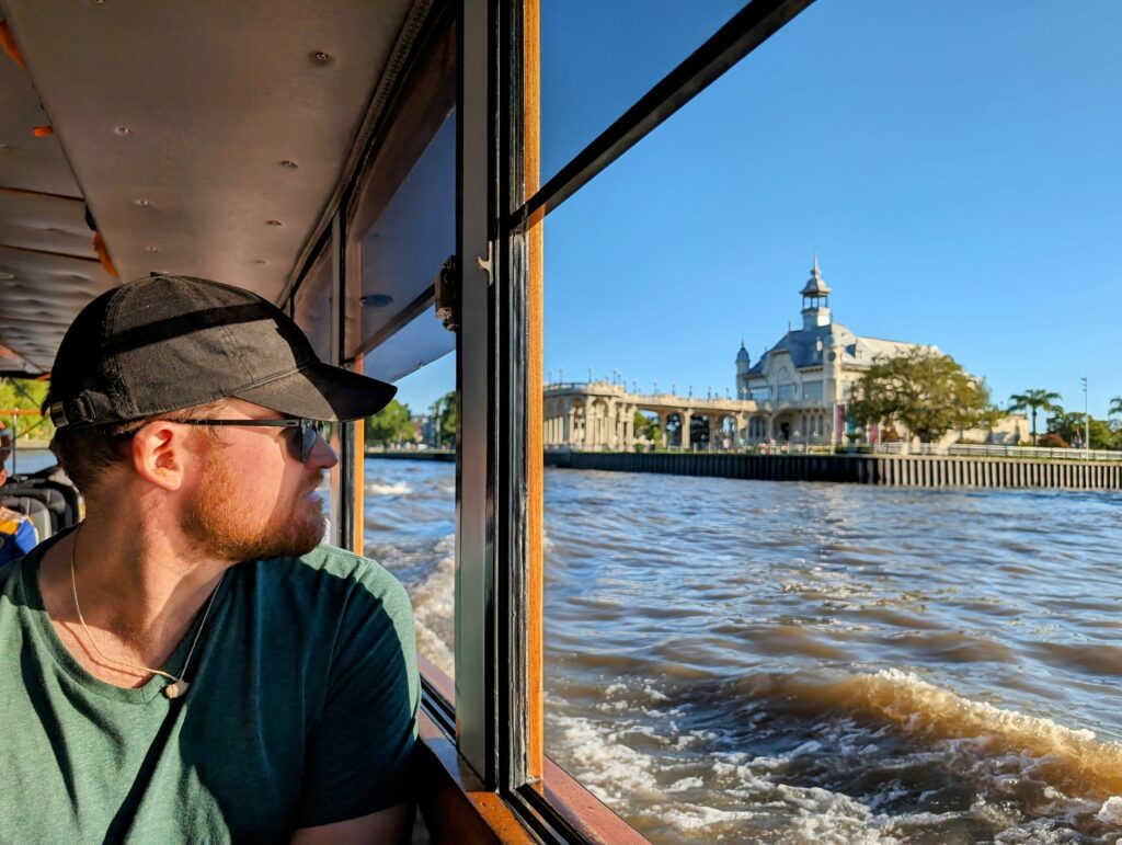 Man looking out of a boat at a river with a building on the bank