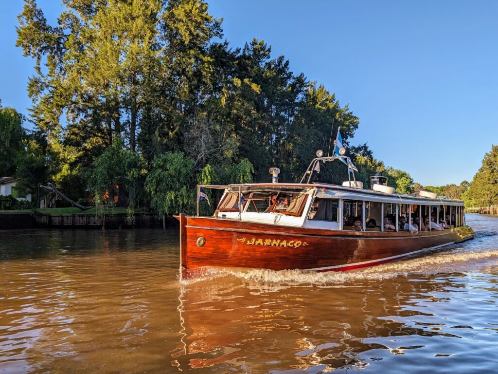 A wooden boat gliding down a river, surrounded by lush trees.