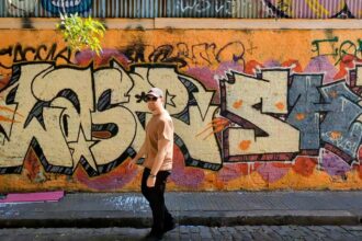 Man standing in front of an orange and pink mural in Palermo Soho, Buenos Aires, Argentina while traveling