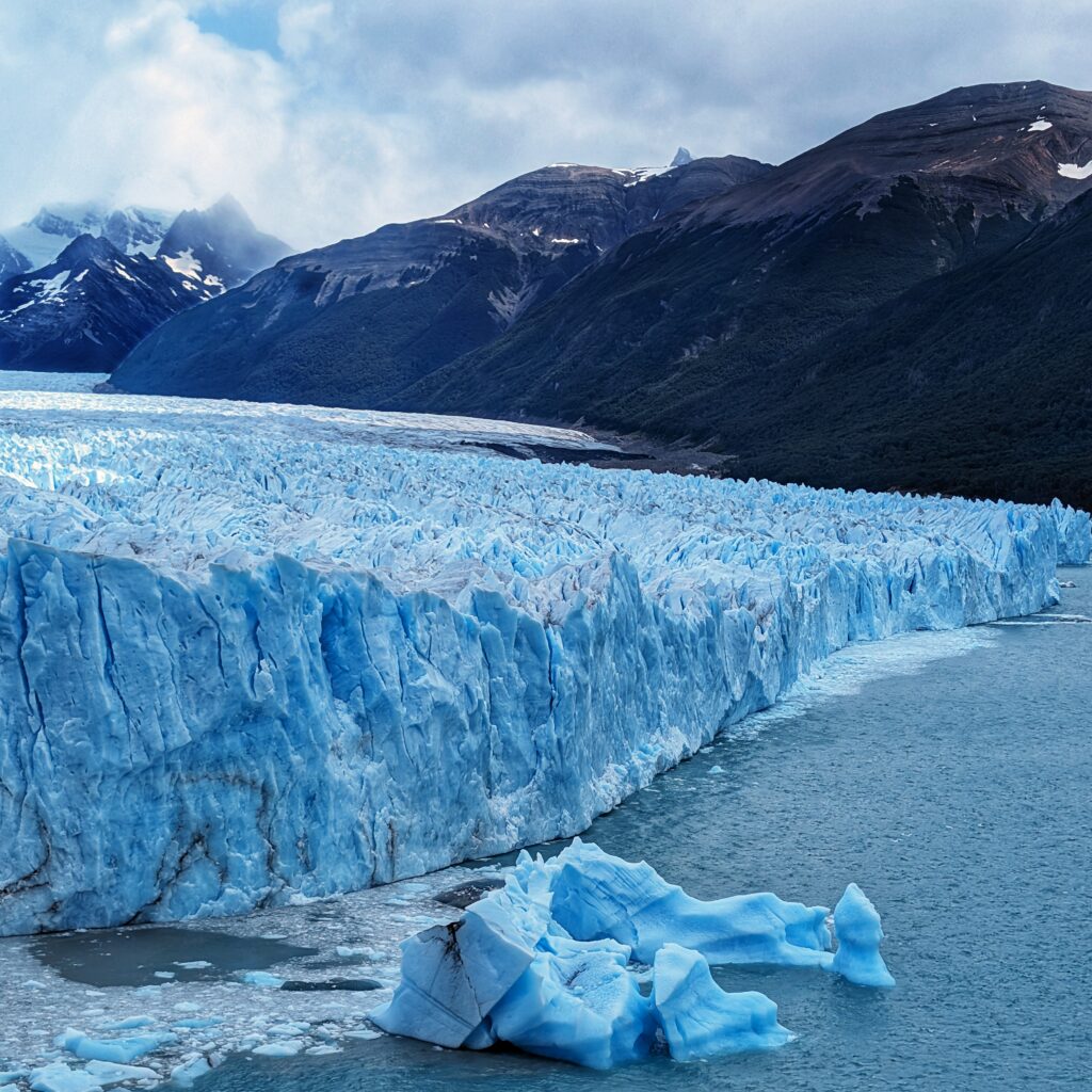 A gigantic glacier with glistening blue ice fragments scattered across its vast expanse.