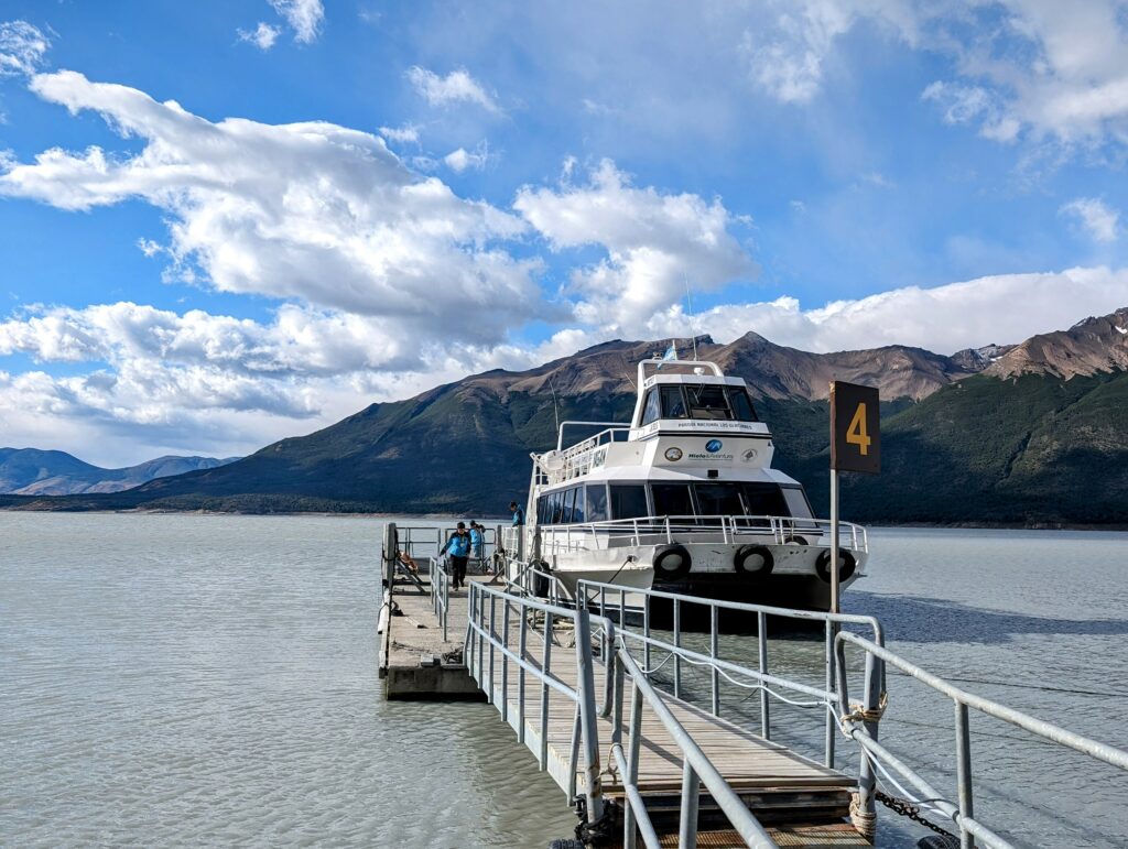 A boat docked at a pier with majestic mountains in the background, creating a serene and picturesque scene.