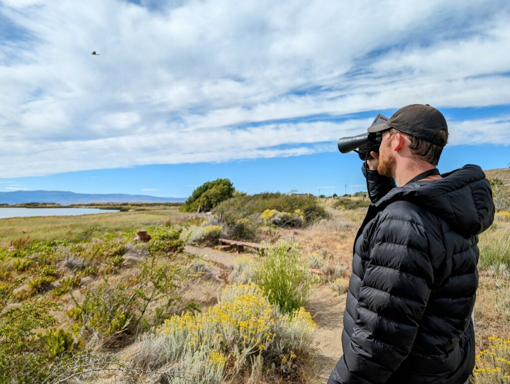 A man looking across a beautiful landscape with binoculars