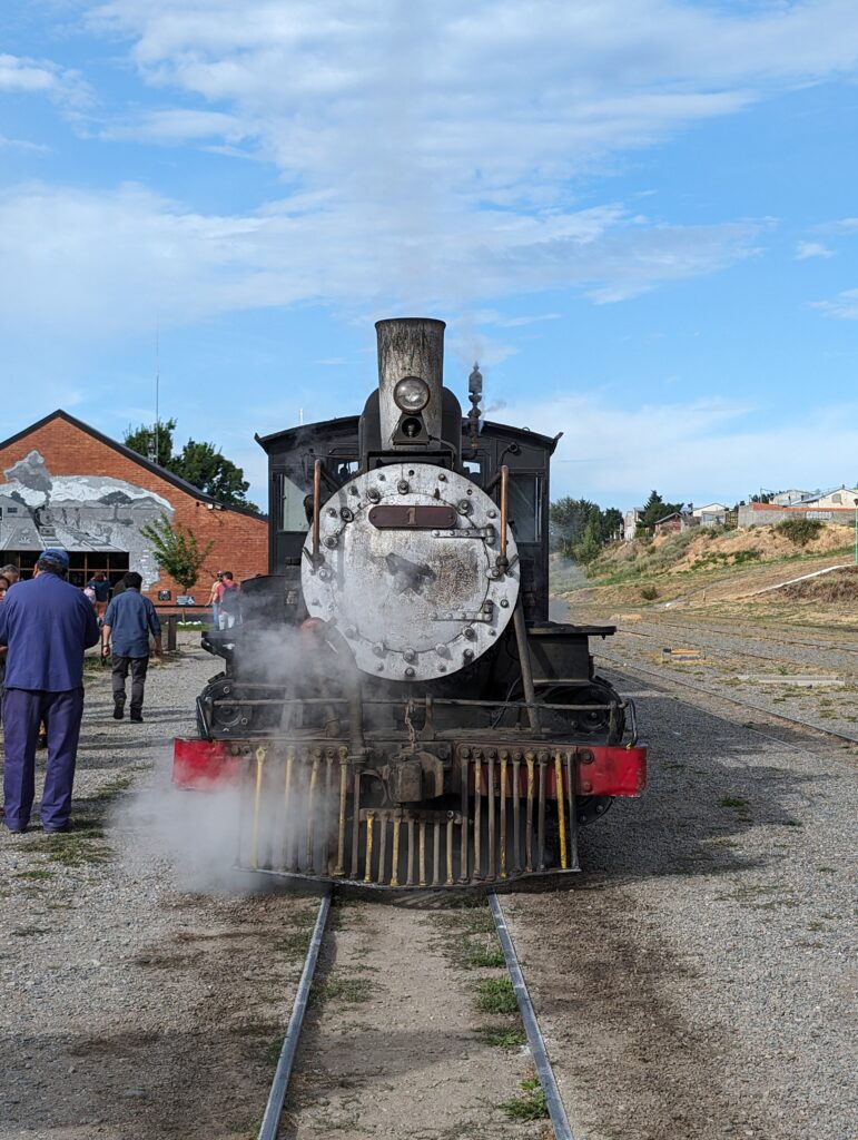 A black and red steam train waiting on tracks with a blue sky in the background