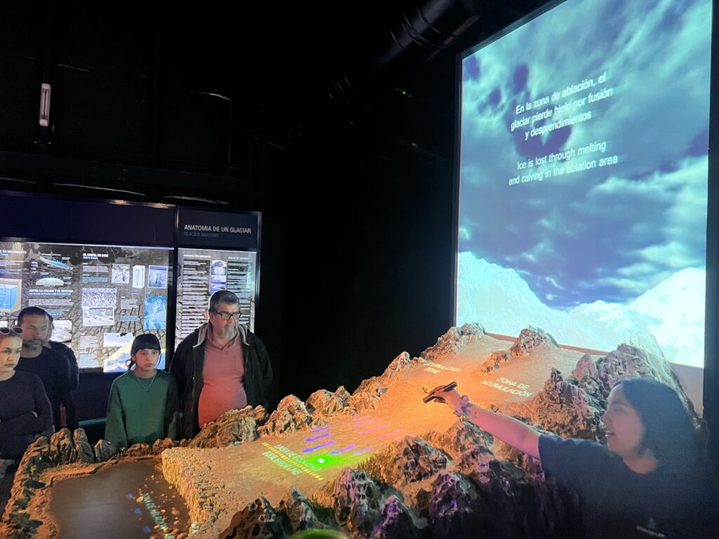 People observing a glacier model exhibit.