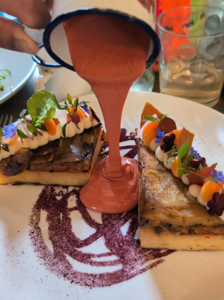 Pouring sauce over a plate of two cakes at a restaurant in La Paz
