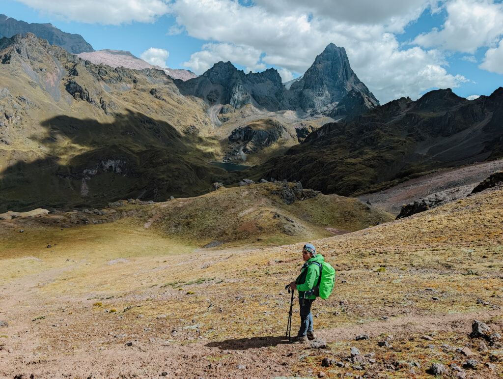 A man standing on a trail with mountains behind him on the Lares Trek