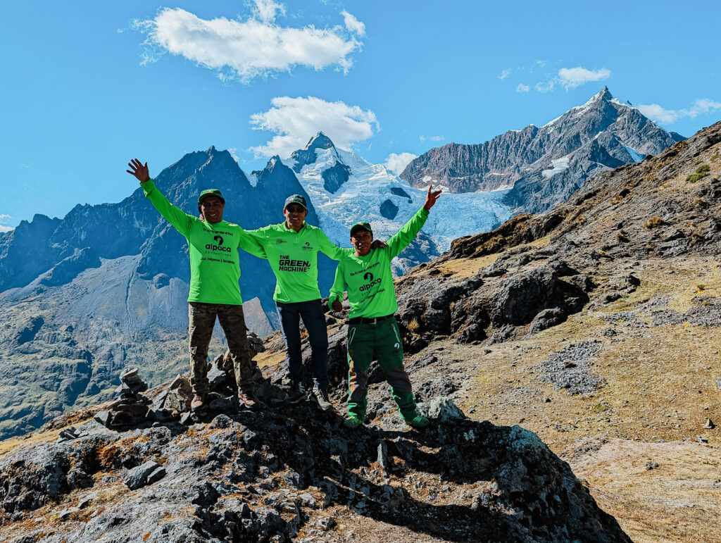 Three guys with green t-shirts standing in front of a mountain on the Lares Trek