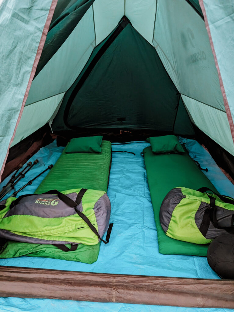 A tent with two mattresses, pillows, and duffle bags during the Lares Trek