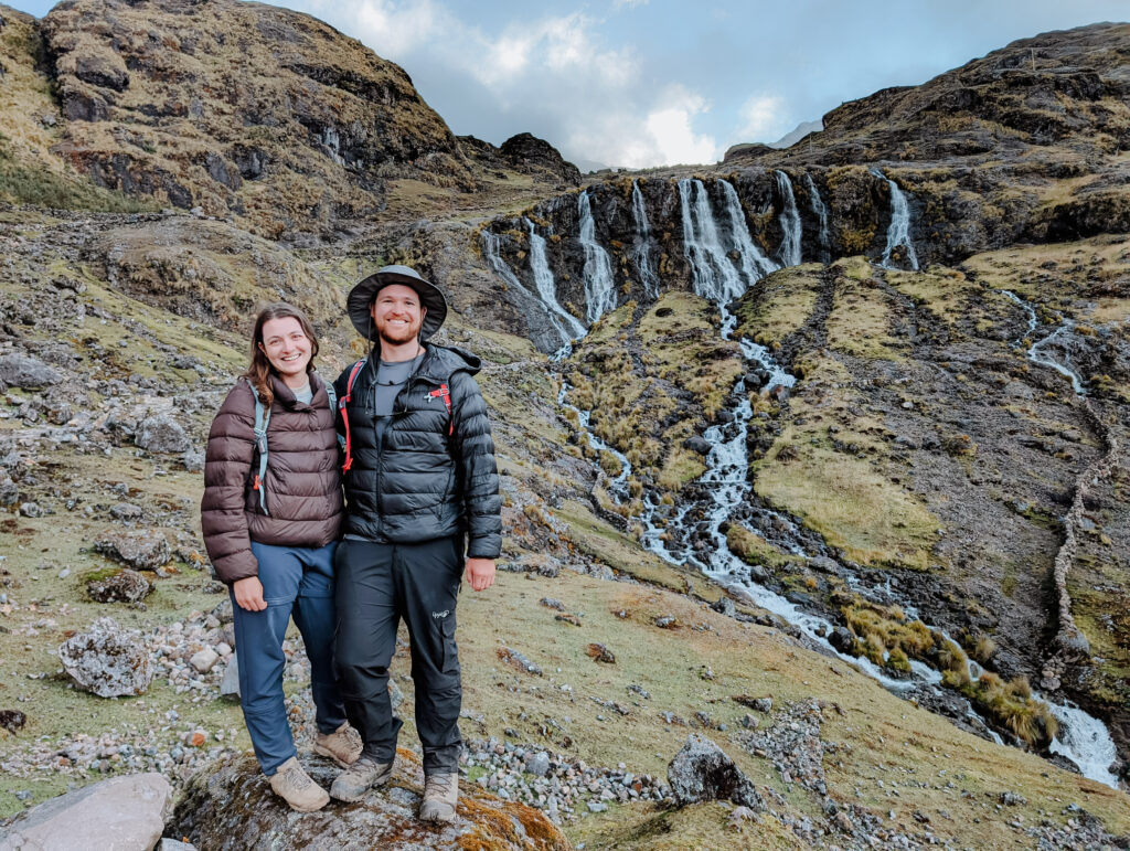 Two people standing in front of a waterfall with 7 streams on the Lares Trek