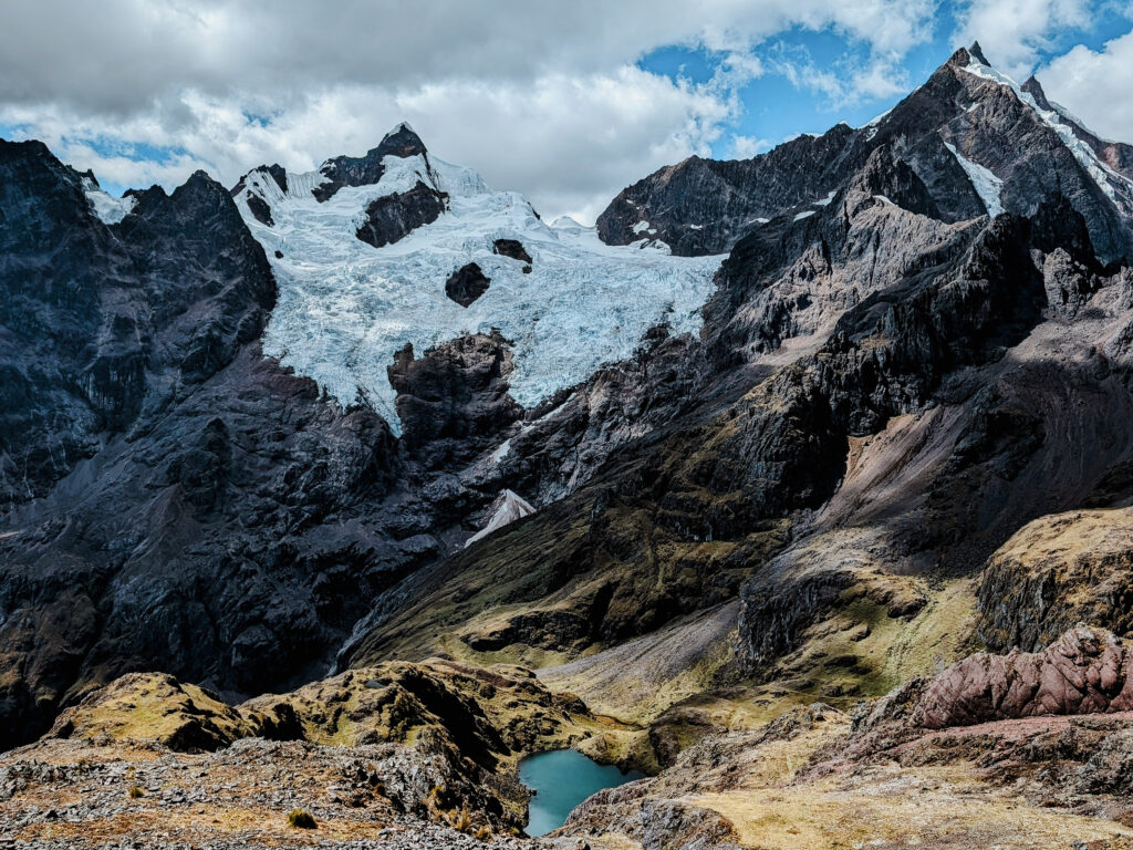 A turquoise lagoon at the base of some snow-capped mountains on the Lares Trek