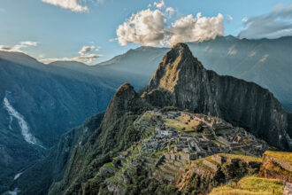 Machu Picchu with rays of sunshine coming over the mountains at sunset