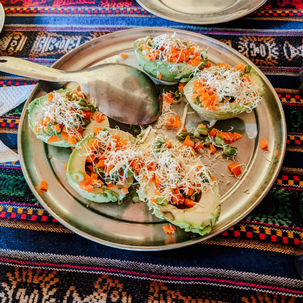 A plate of avocados sliced in half and filled with a carrot salad for a meal on the Lares Trek