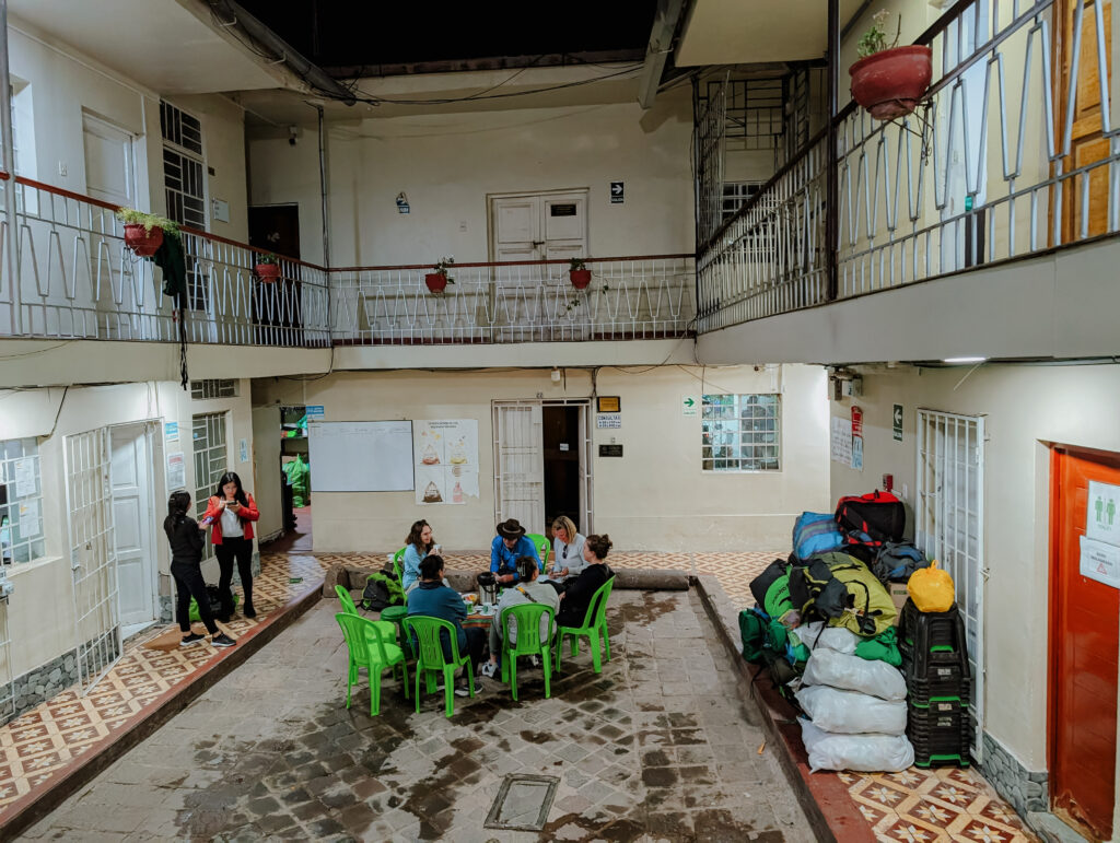 A courtyard within a building with green chairs in a circle to talk about a briefing on the Lares Trek