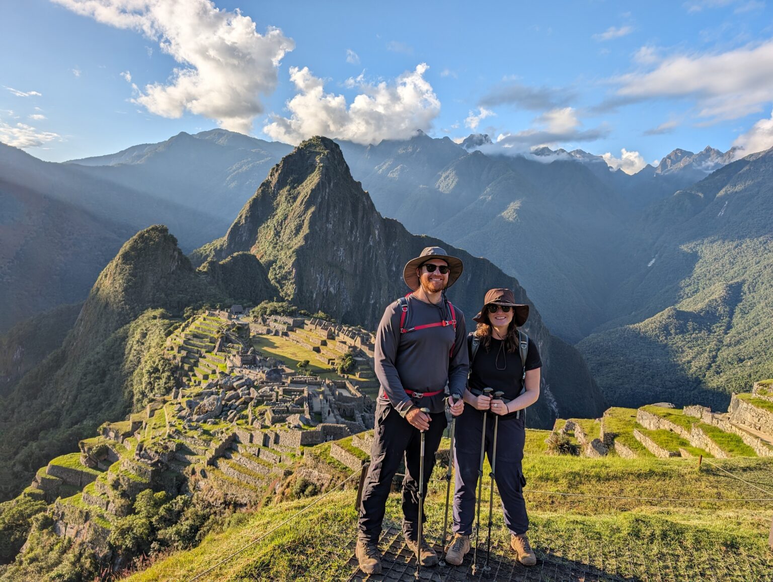 Two people standing in their hiking gear in front of Machu Picchu