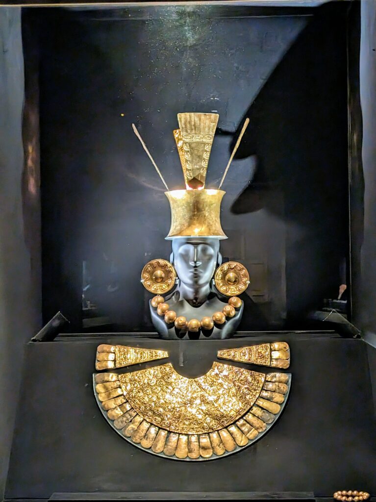 A bust display with gold jewelry and crowns on display in an archaeological museum in Lima