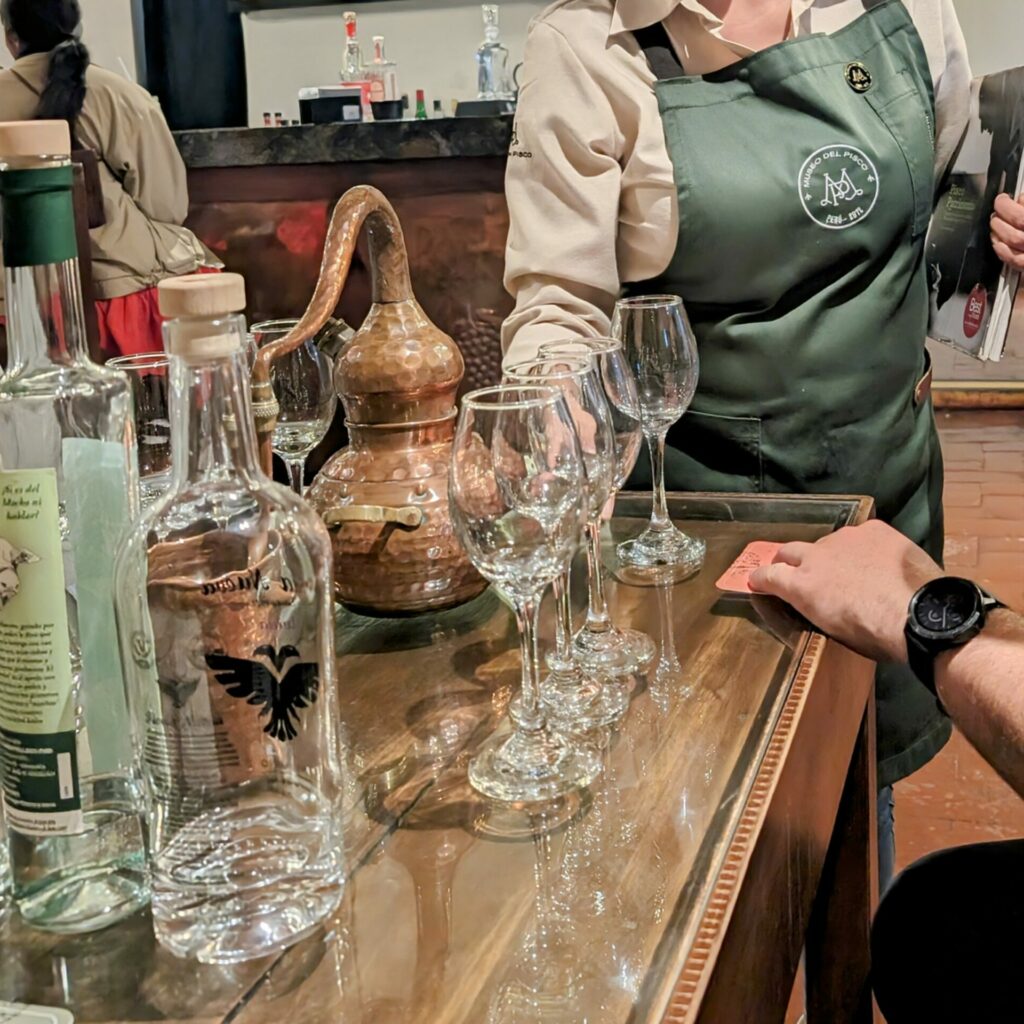 Glass bottles and glasses lined up in front of a person and a waitress at a tasting in Lima