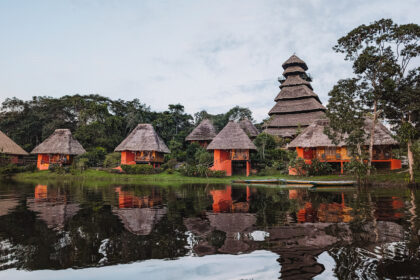 Some red cabins at the edge of a lake in the rainforest for Napo Wildlife Center