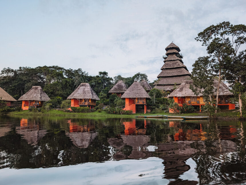 Some red cabins at the edge of a lake in the rainforest for Napo Wildlife Center