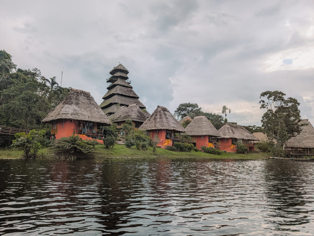 Some red cabins at the edge of a lake in the rainforest for Napo Wildlife Center