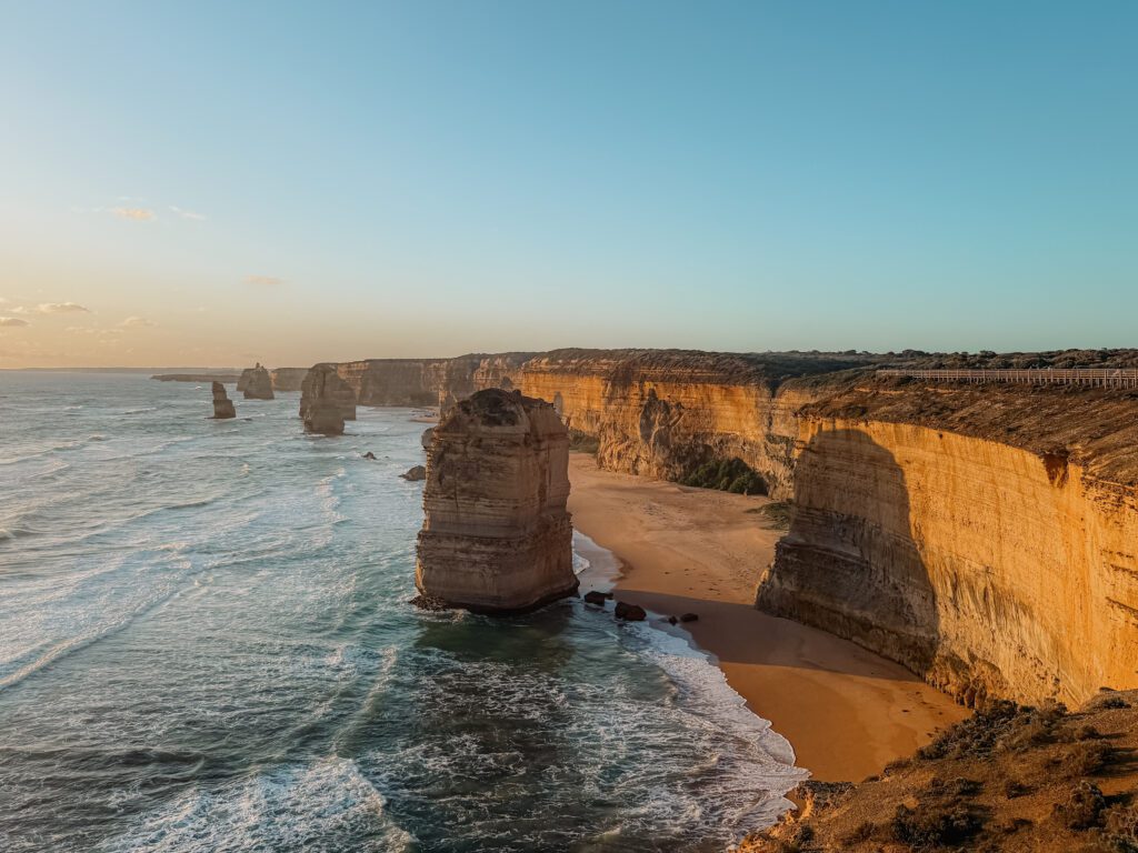 Rock formations in the ocean adjacent to a beach and cliff as seen when driving the Great Ocean Road