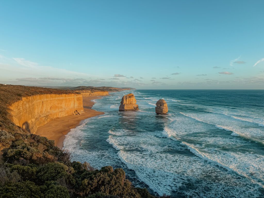 Rock formations in the ocean adjacent to a beach and cliff as seen when driving the Great Ocean Road