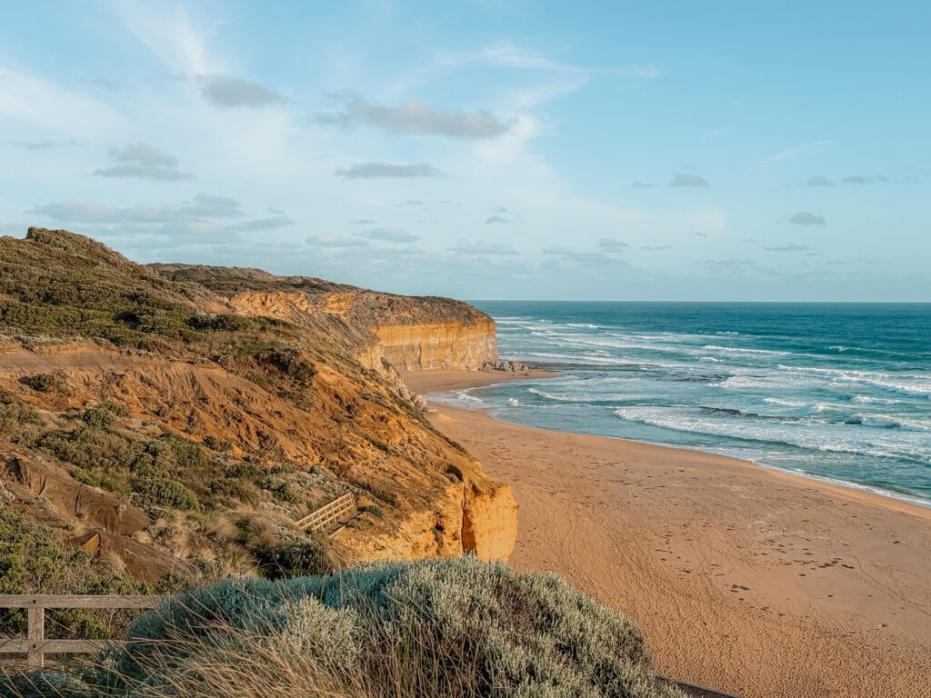 A beach between the ocean and a cliffside as seen when driving the Great Ocean Road