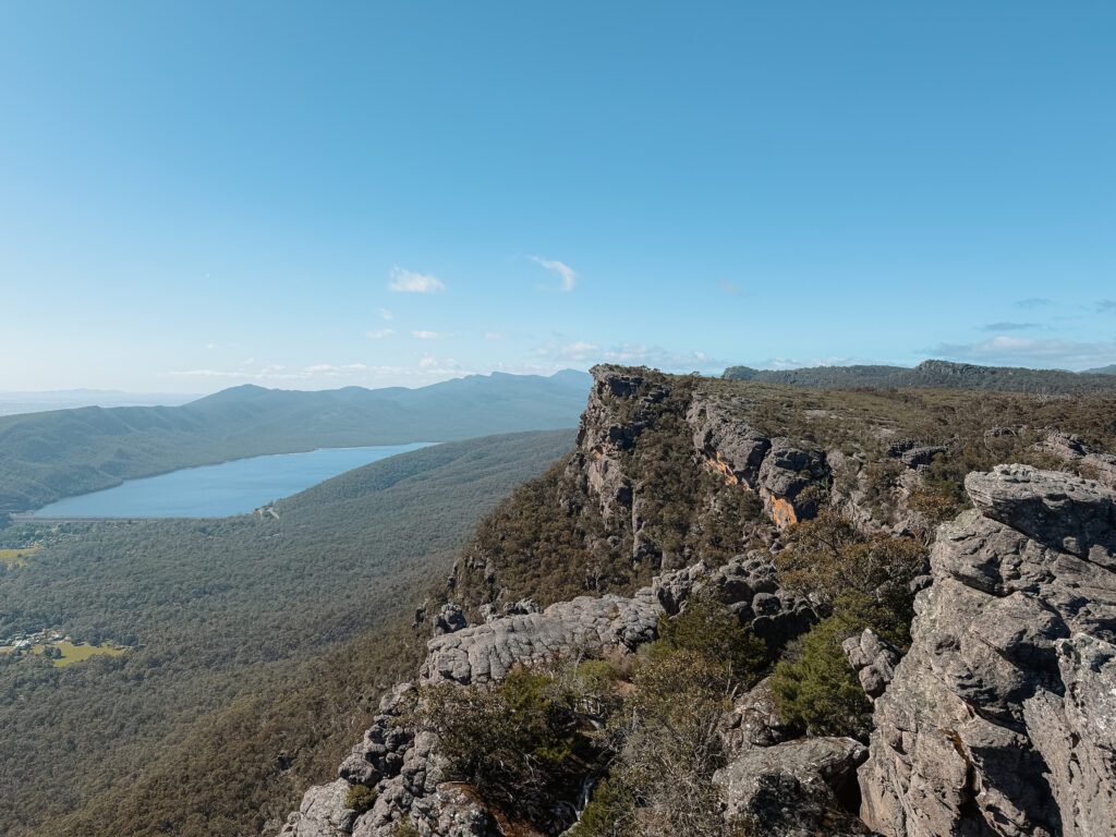 View over a cliff edge of the cliffside and valley with a lake in the Grampians